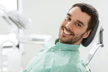 man sitting in dentist exam chair | tooth extractions scarborough on