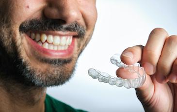 patient holding invisalign clear plastic aligner | orthodontics scarborough on