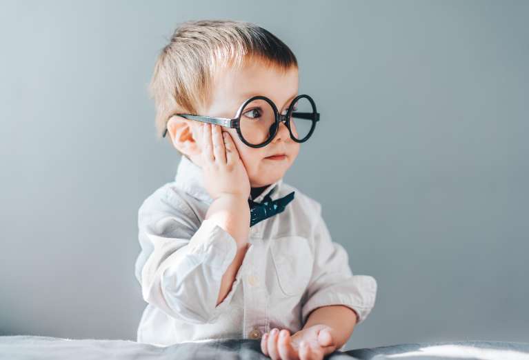 A young boy with glasses and a bow tie promotes early dental care for healthy smiles.