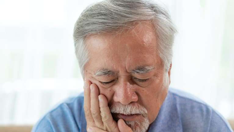 A picture on elder man clutching his jaws depicting TMJ and Jaw Pain 